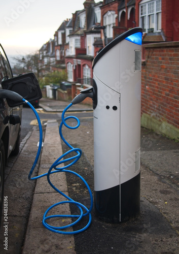 An electric vehicle being charged at a charging station at a residential street in London, UK in the evening.