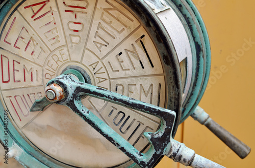 Valokuva Close up of an antique, verdigris green bronze, French ship's engine order telegraph (EOT) or chadburn communication device, with worn red words on a cream white dial face against a canary background