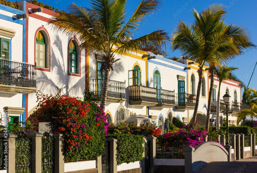 Colorful buildings with palm trees and flowers on sunny day in Puerto de Mogan, Gran Canaria. Summer vacation, travel destination in Canary Islands, Spain