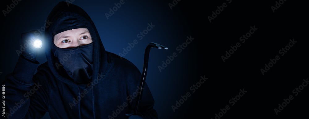 Maskierter Einbrecher in der Nacht mit Brecheisen und blau schwarzen Hintergrund - obrazy, fototapety, plakaty 