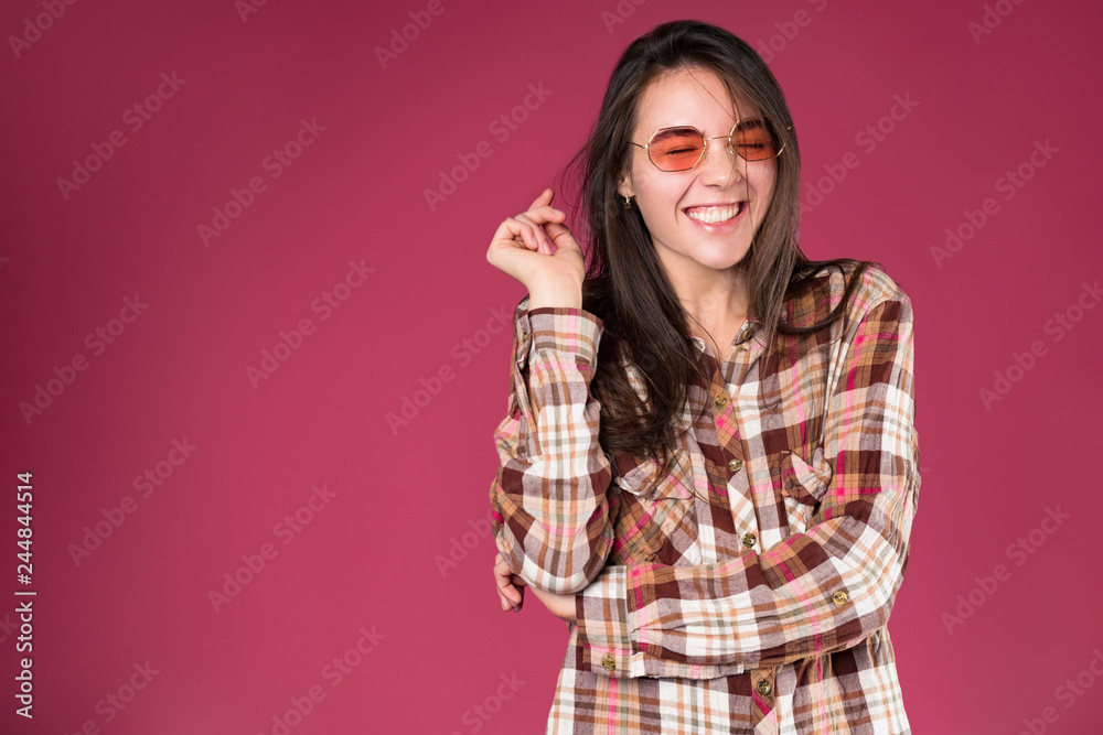 Long haired young brunette stylish girl smiling and laughing on pink background Long haired young brunette stylish girl smiling and laughing on pink background