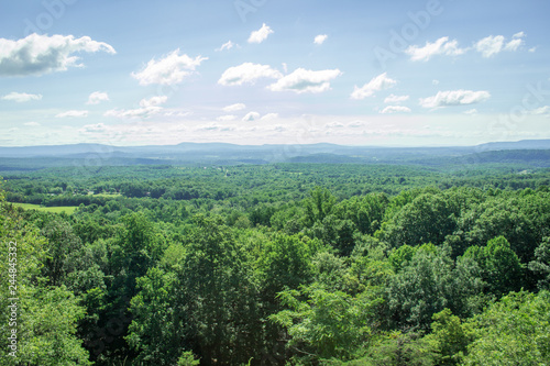 Aerial Photo of a Forest in the Countryside - with a Long Stretch of Green Trees  Patches of Farmland and Mountains in the Distance on a Bright  Summer Day in the Appalachian United States