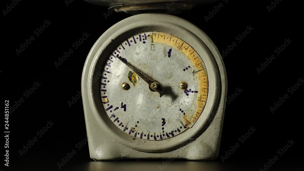 Old fashioned kitchen scales with a spinning pointer on a black background Old fashioned kitchen scales with a spinning pointer on a black background