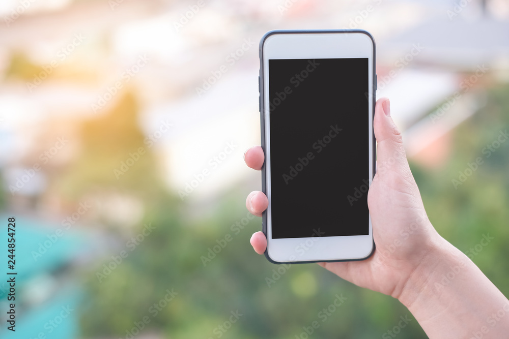 hand holding smartphone or mobile phone with city building background and copy space.