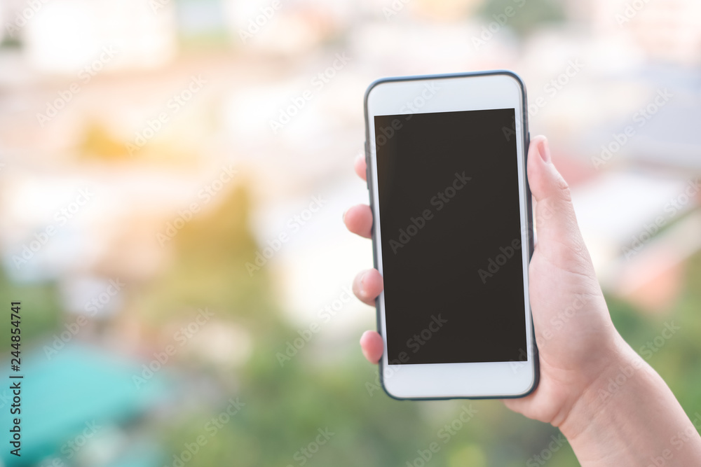 hand holding smartphone or mobile phone with city building background and copy space. hand holding smartphone or mobile phone with city building background and copy space.