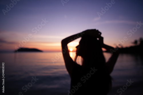 Blurred abstract background. Silhouette of a beautiful slim young woman on a background of bright colorful sunset on a tropical beach