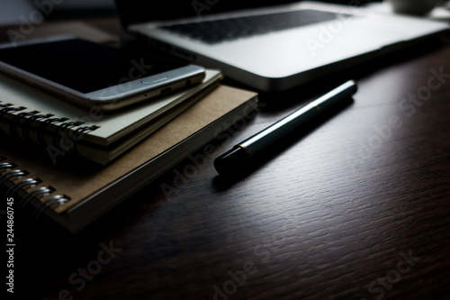 Close up office desk table with laptop, note book, mobile coffee and pen. Selective focus. Business concept. Copy space.