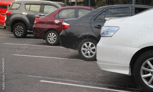 Closeup of back or rear side of white car and other cars parking in parking lot in the evening of sunny day. 