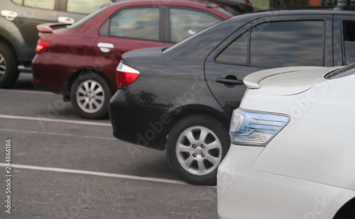 Closeup of rear side of white car and other cars parking in parking lot in the evening of sunny day.  © Amphon