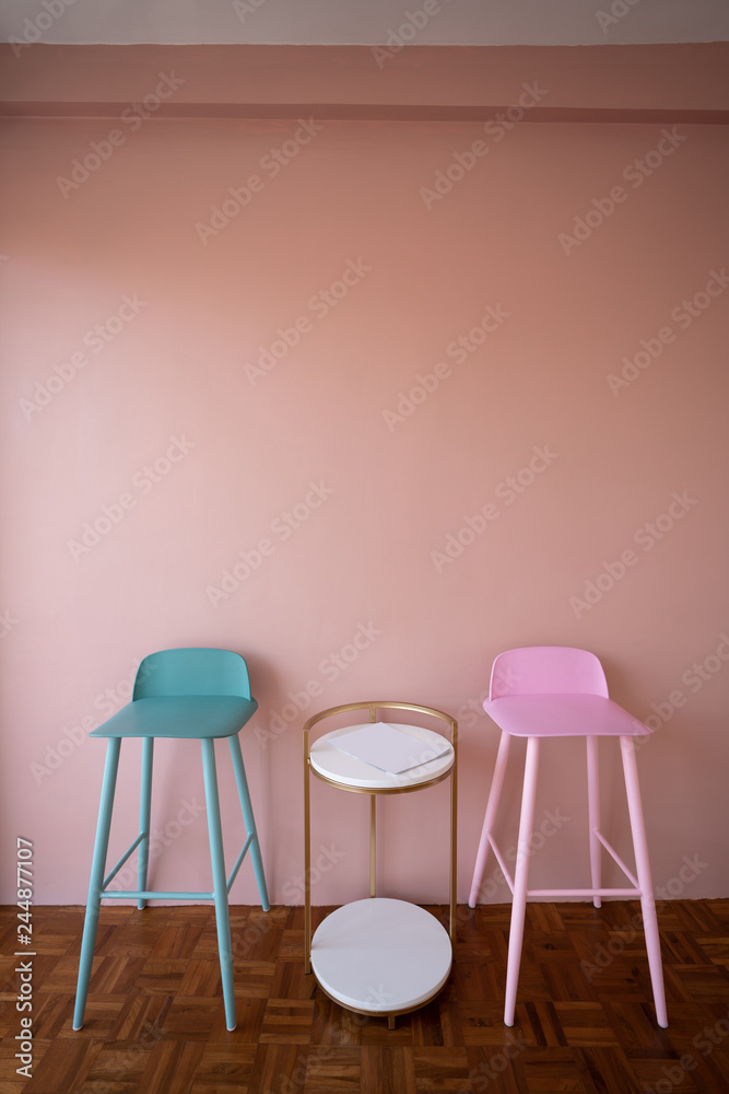 Setting of green and pink high stools with high side table on pink background wall / cozy interior conept / pink wall decoration Setting of green and pink high stools with high side table on pink background wall / cozy interior conept / pink wall decoration