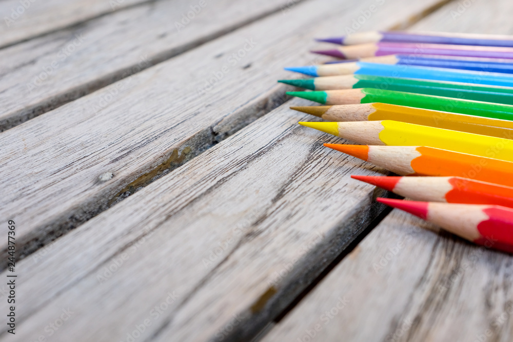 Fototapeta premium Colorful rainbow color pencils on wooden plank