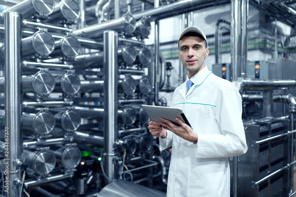 man in a white robe with a tablet in his hands is in the production shop at the factory man in a white robe with a tablet in his hands is in the production shop at the factory