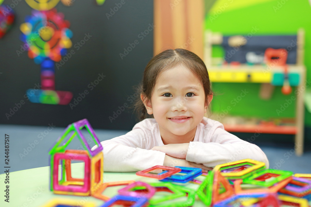 Fototapeta premium Little child girl playing Magnets toy for brain development.