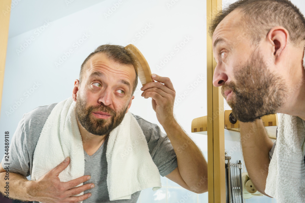 Obraz premium Man using comb in bathroom