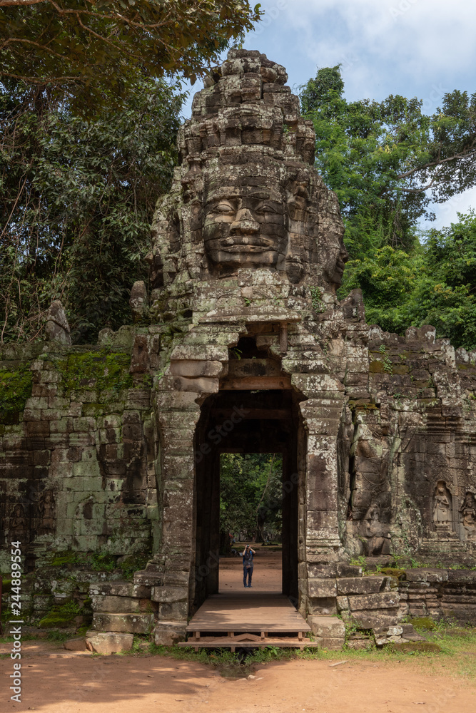 Tourist photographing stone entrance with Buddha face