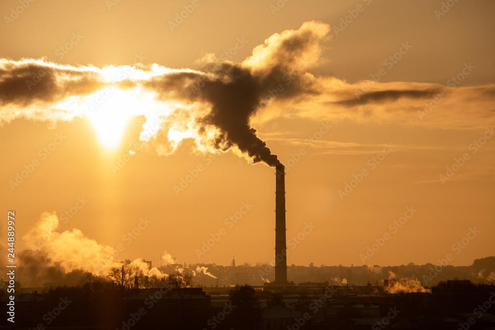 Steaming cooling towers and smoking industrial stacks against sunset gradient sky