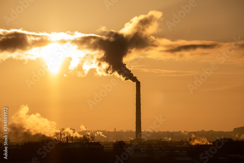 Steaming cooling towers and smoking industrial stacks against sunset gradient sky