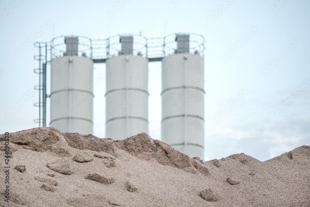 Large piles of construction sand and gravel used for asphalt production and building. Limestone quarry, mining rocks and stones. Factory in the background. Empty space for text of logo Large piles of construction sand and gravel used for asphalt production and building. Limestone quarry, mining rocks and stones. Factory in the background. Empty space for text of logo