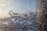 Frosty snowflake pattern on the window glass and city lights