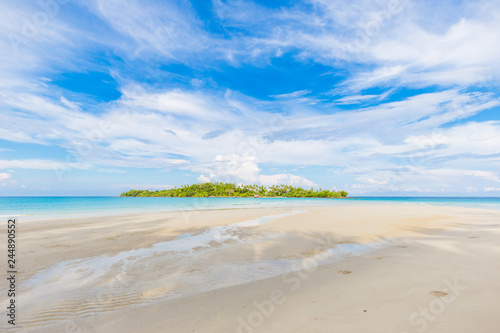 Idyllic white sand beach seascape blue sky with island