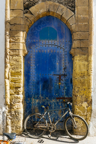 Old blue wrabic door in Morocco (Marrakesh) and bicycle. Traditional oriental style and design in Muslim countries © uladzimirzuyeu