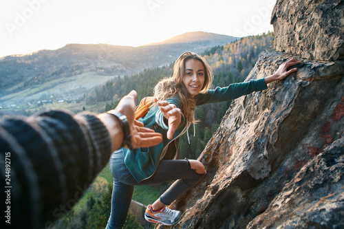 Foto first person view of a young pretty woman hiker climbed on the cliff, looking co