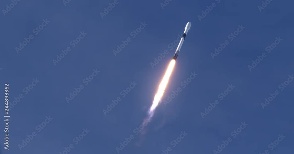 Rocket launching into space through blue skies and clouds. Flames and smoke trail behind the rocket. 4K video at 120 fps slow motion. With audio.