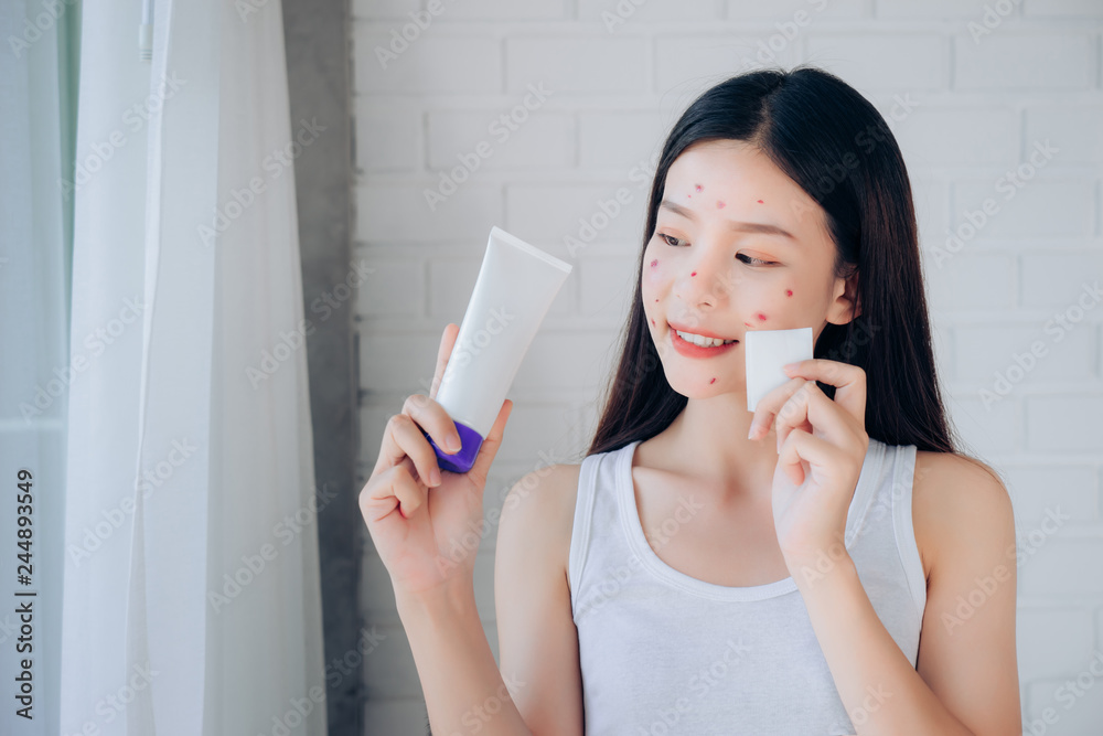 Young Beauty Asian Woman Cleaning Face with Cotton and Cleansing foam Skincare for Reduce acne problems Her Smile and Happy Morning in White Bedroom. Young Beauty Asian Woman Cleaning Face with Cotton and Cleansing foam Skincare for Reduce acne problems Her Smile and Happy Morning in White Bedroom.