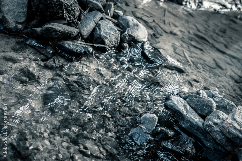 close up of stone that use to make weir in river with water steam flowing, look from the top. made in dramatic tone