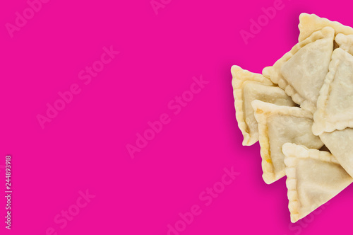One heap of prepared vareniki with potato or cottage cheese or meat or cabbage on pink background with copy space for your text