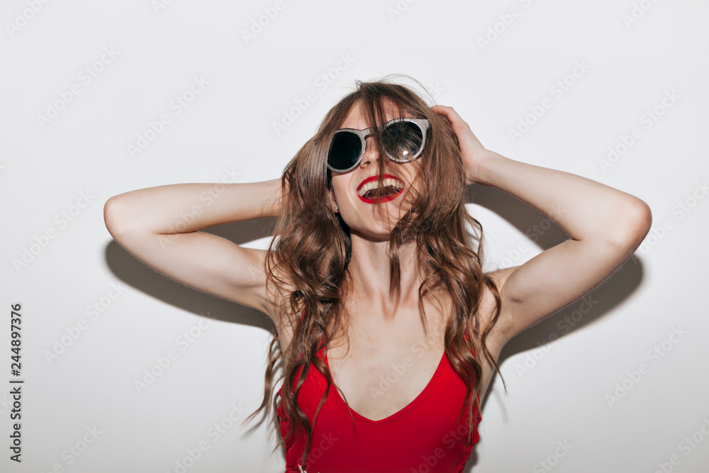 Close up portrait of emotional stylish hipster woman in black glasses and red t-shirt over isolated white wall