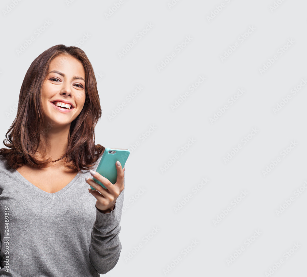Young beautiful happy woman using smart phone. Isolated on grey background Young beautiful happy woman using smart phone. Isolated on grey background