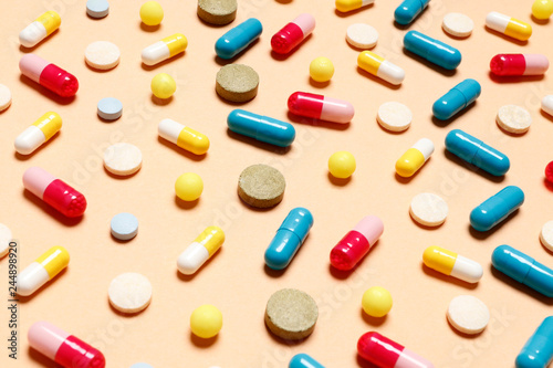 Multi-colored vitamins on a pink background. Place for text. Top view.