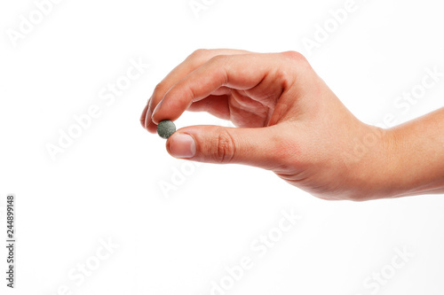 spirulina pill in hand isolated on white background