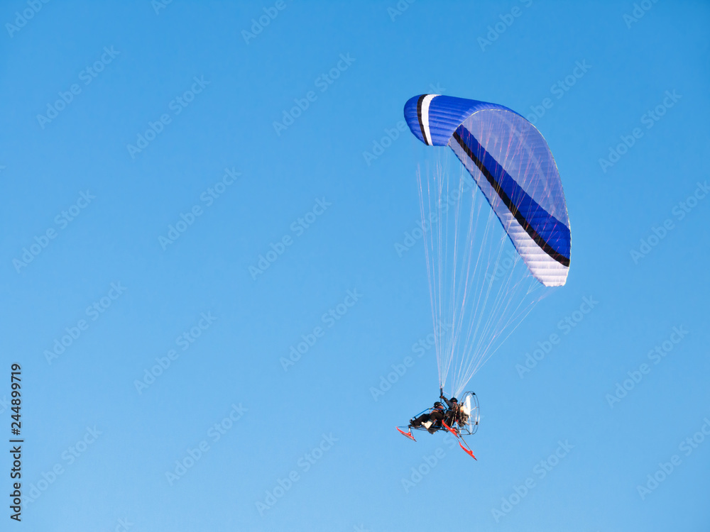 Man flying on paraglider, glider with motor. Vehicle in clear blue sky. Man flying on paraglider, glider with motor. Vehicle in clear blue sky.