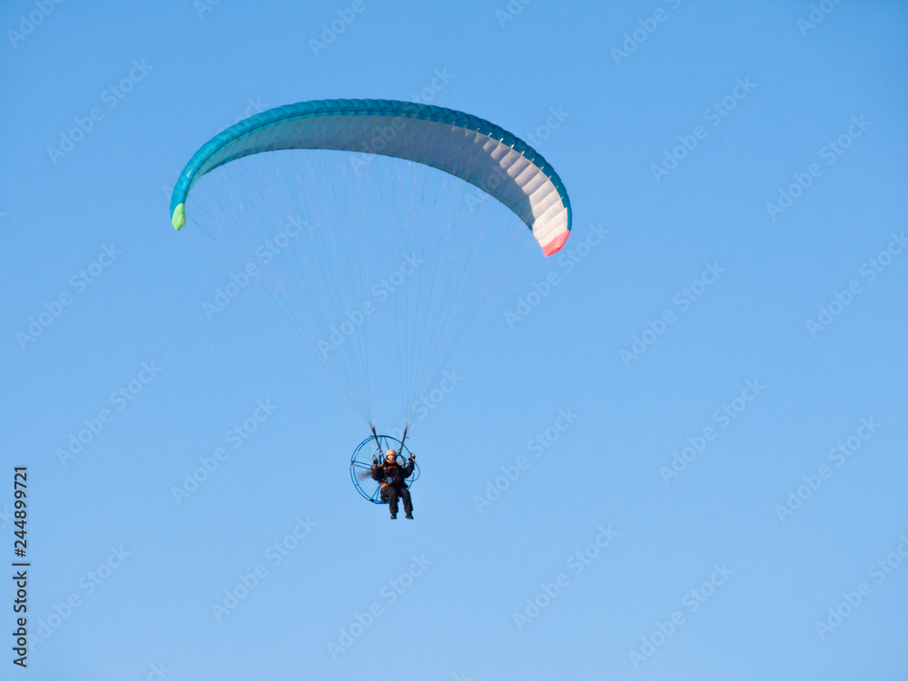 Man flying on paraglider, glider with motor. Vehicle in clear blue sky. Man flying on paraglider, glider with motor. Vehicle in clear blue sky.