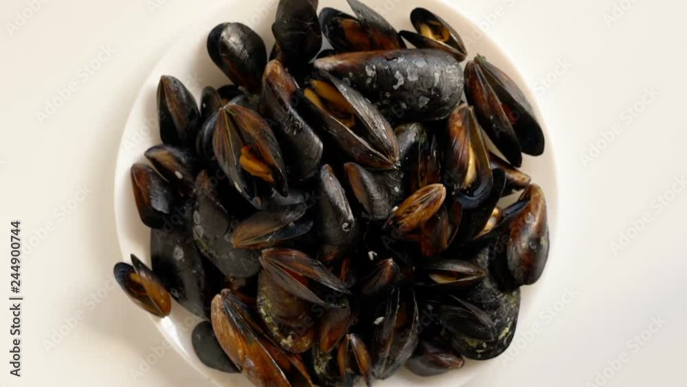 Top view cooked sea mussels on white plate rotating Top view cooked sea mussels on white plate rotating