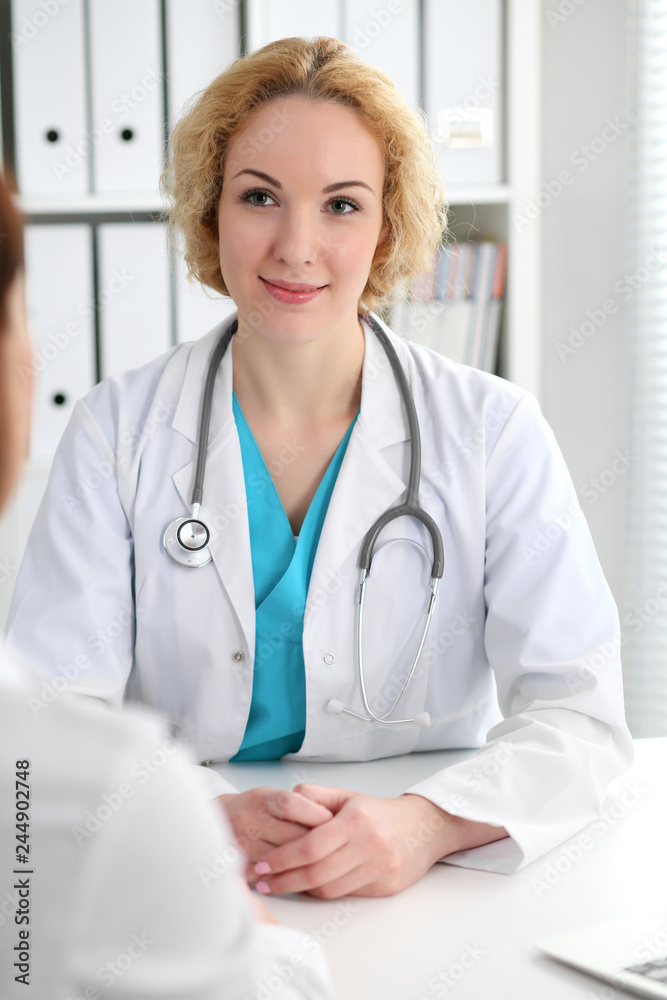 Happy blonde female doctor and patient discussing medical examination results. Medicine, healthcare and help concept Happy blonde female doctor and patient discussing medical examination results. Medicine, healthcare and help concept