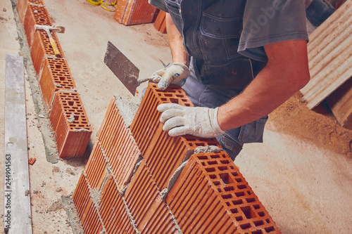 Real construction worker bricklaying the wall indoors.