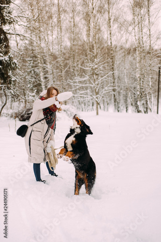 Woman playing with a dog in winter park .Cute girl in a winter park.