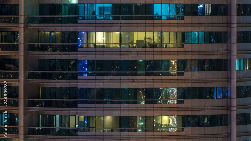 Glowing windows in multistory modern glass residential building light up at night timelapse. Glowing windows in multistory modern glass residential building light up at night timelapse.