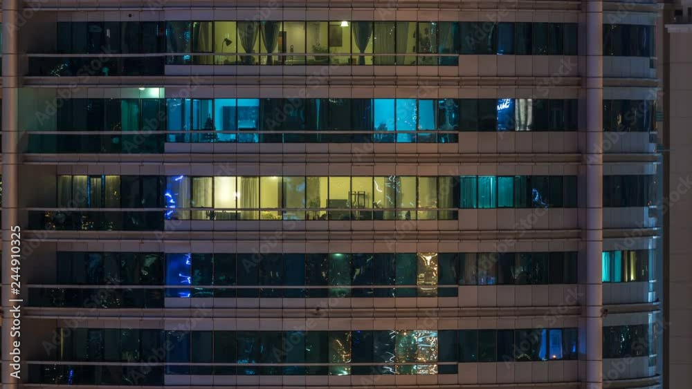 Glowing windows in multistory modern glass residential building light up at night timelapse. Glowing windows in multistory modern glass residential building light up at night timelapse.