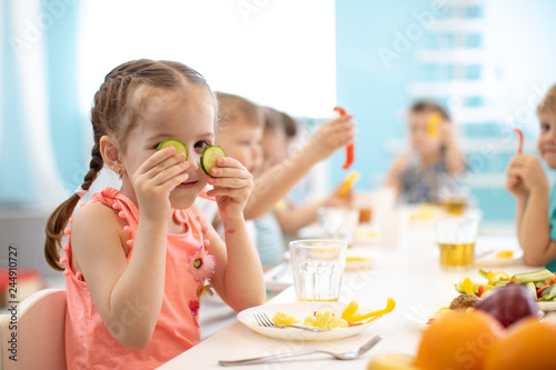 funny children eating healthy food in kindergarten or daycare