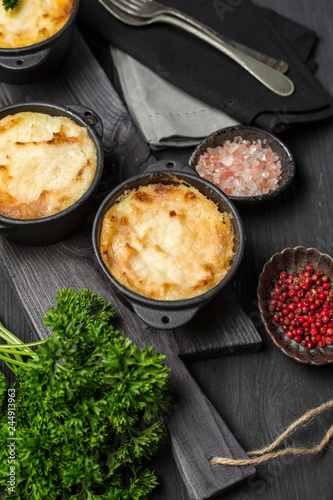 Shepherd's pie, british casserole in cast iron pan, with minced meat, mashed potatoes and vegetables, on dark background, vertical composition