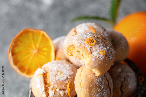 Homemade orange crinkle cookies with powdered sugar icing on gray background, close up
