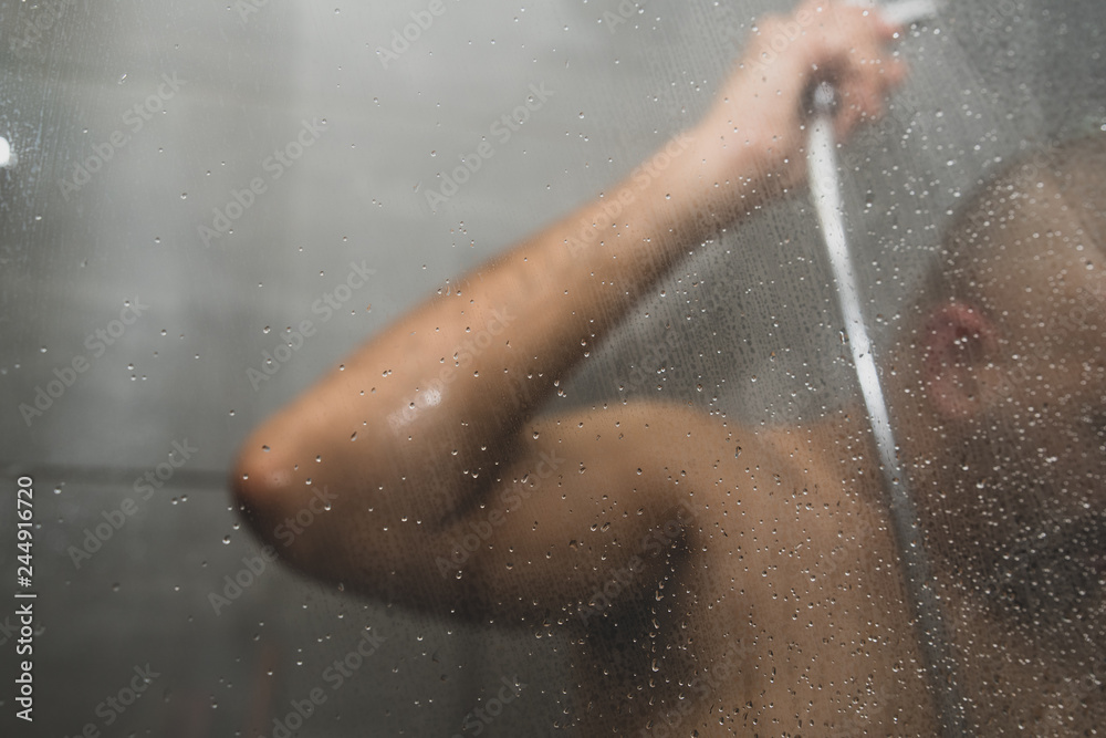 British Asian man taking a shower in the shower cubicle - with copy space. British Asian man taking a shower in the shower cubicle - with copy space.