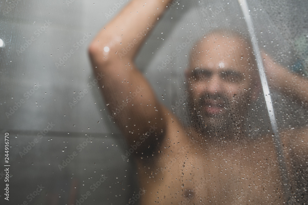 British Asian man taking a shower in the shower cubicle - with copy space. British Asian man taking a shower in the shower cubicle - with copy space.
