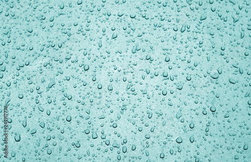 Water drops on car surface in cyan tone.