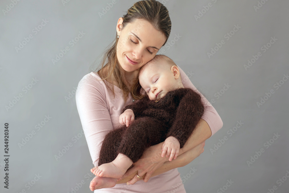 Young mother, caressing her newborn baby boy, holding him in her arms and smiling Young mother, caressing her newborn baby boy, holding him in her arms and smiling
