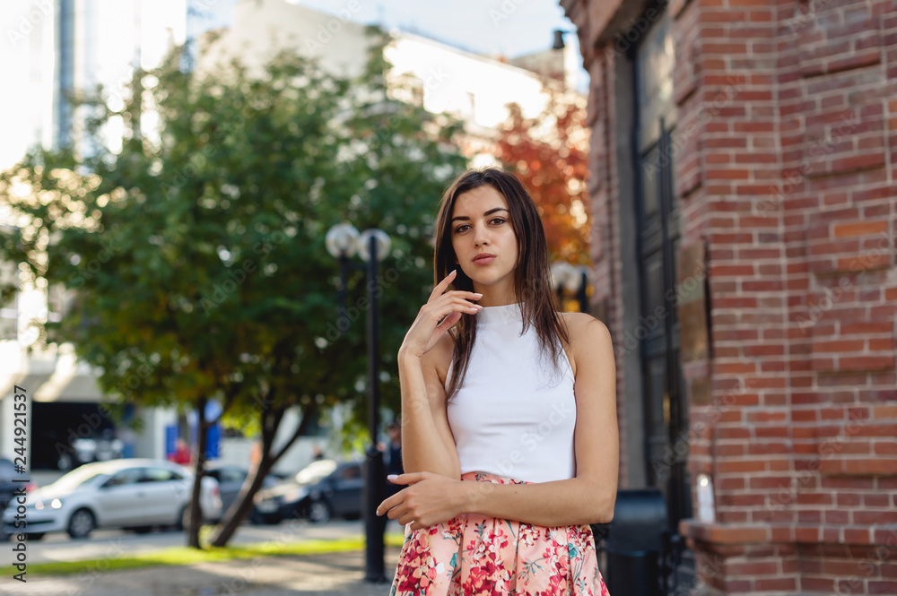 portrait of a young beautiful brunette woman on the street, model posing, women's urban street fashion, warm colors portrait of a young beautiful brunette woman on the street, model posing, women's urban street fashion, warm colors